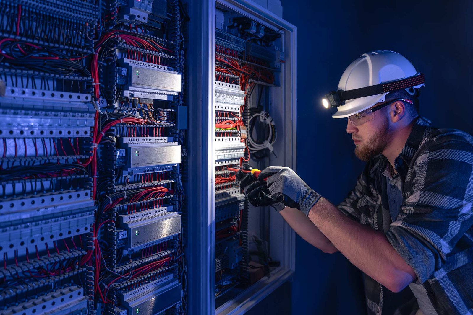 Electrician servicing wiring inside a live distribution panel